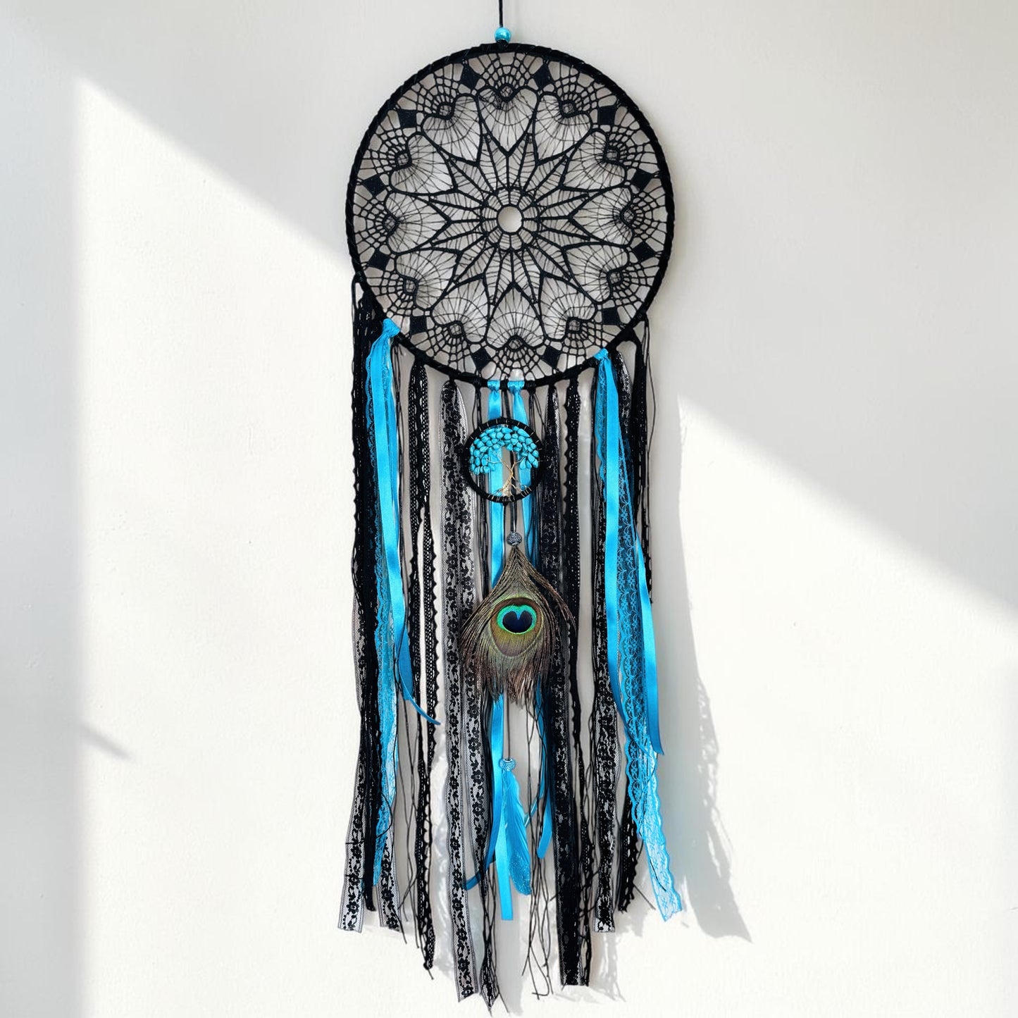 Large turquoise and black dream catcher featuring intricate lace, feathers, and a crystal tree design.