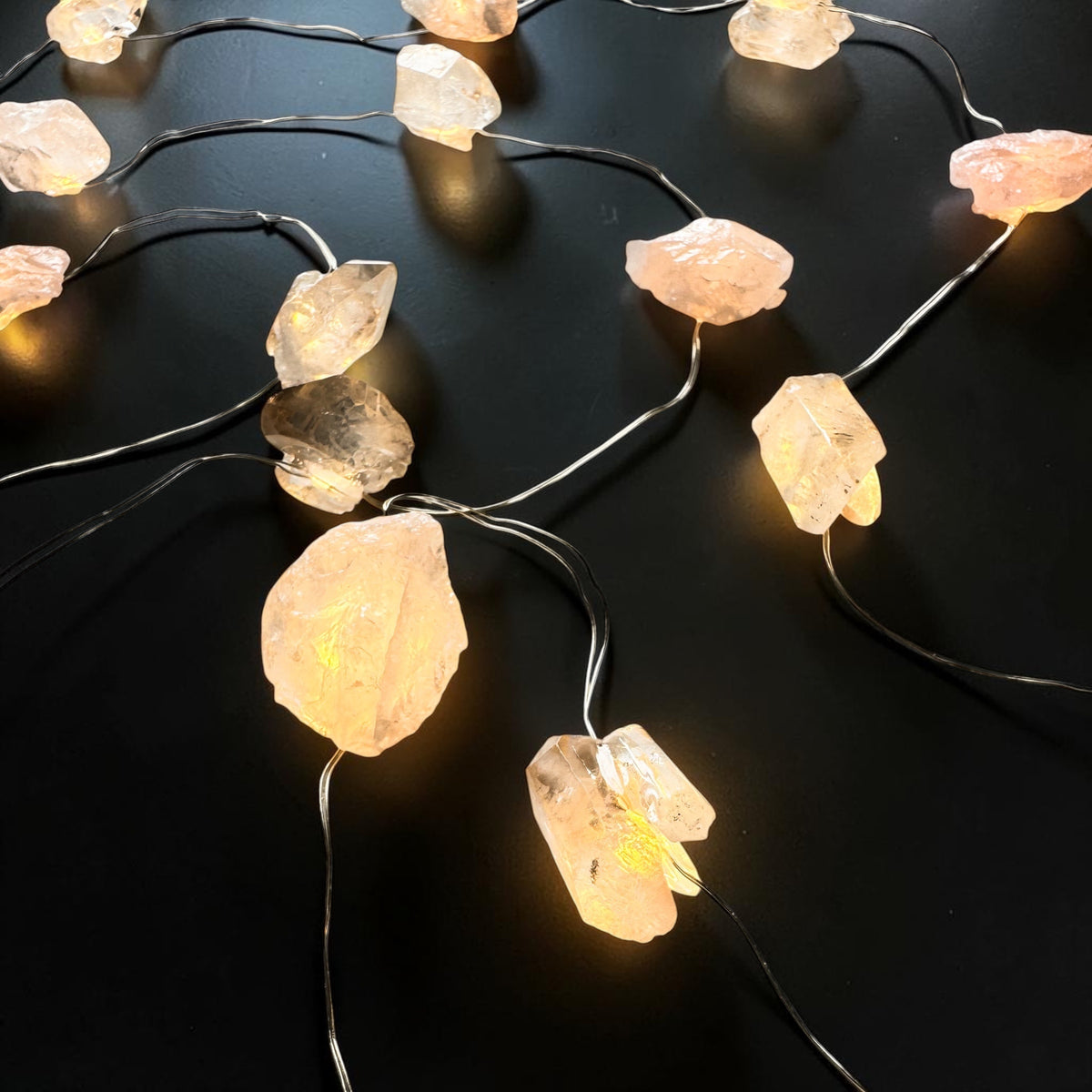 Crystal fairy lights featuring rose quartz and clear quartz on a dark background.