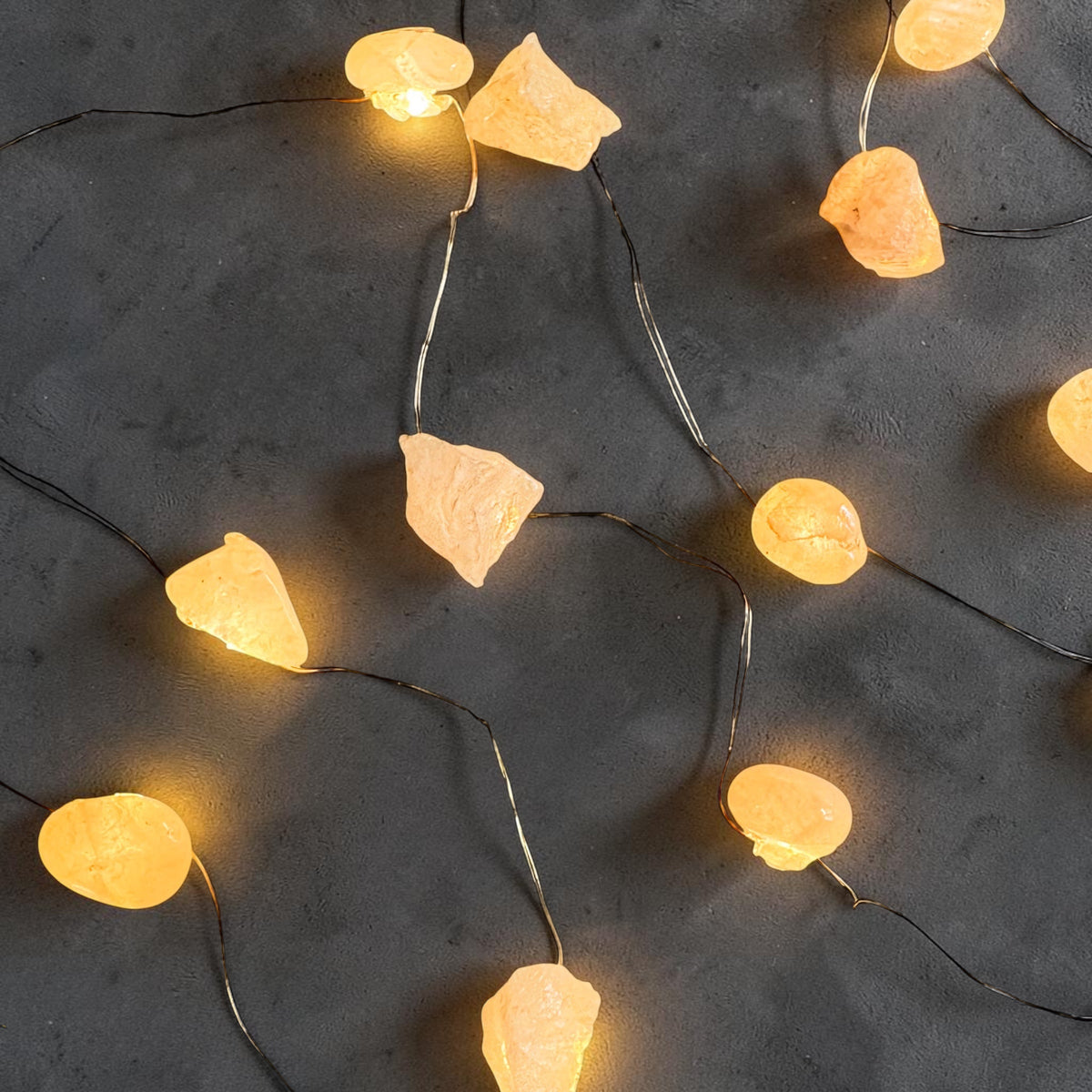 Crystal fairy lights featuring tumbled quartz stones emitting a warm yellow glow on dark background.