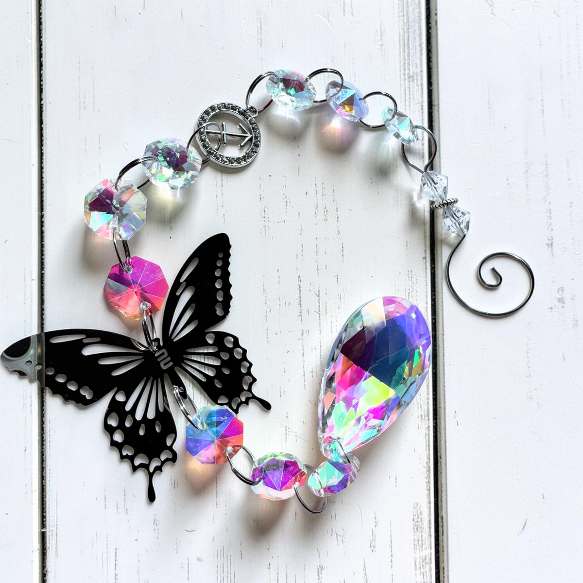 Star sign sun catcher with iridescent beads and black butterfly on a white surface.