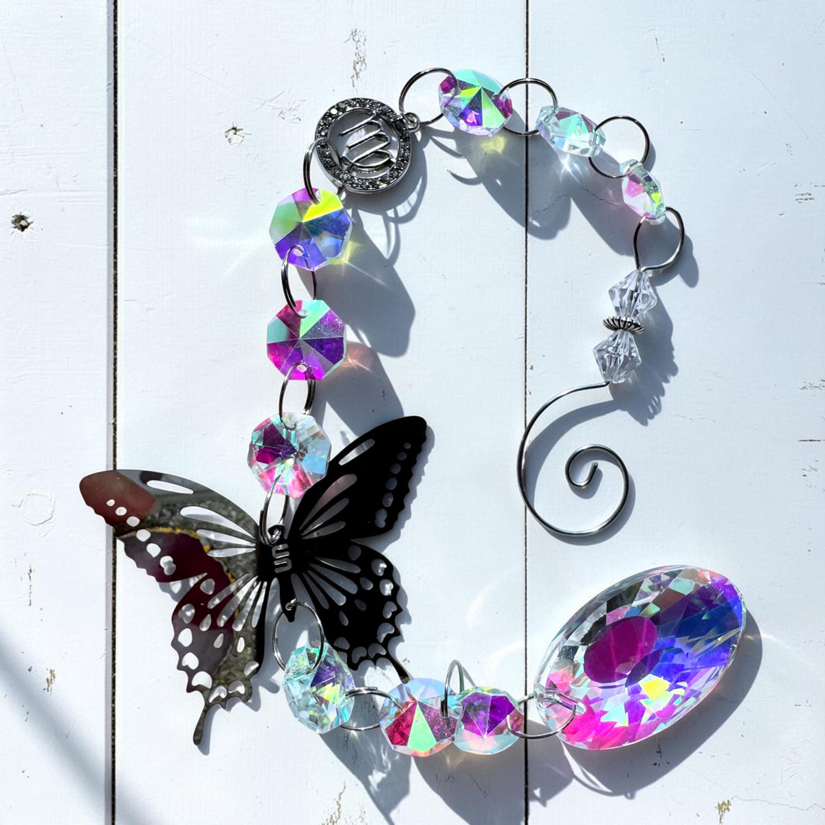 Butterfly Star Sign Sun Catcher with iridescent glass and metal details, casting colorful light reflections.