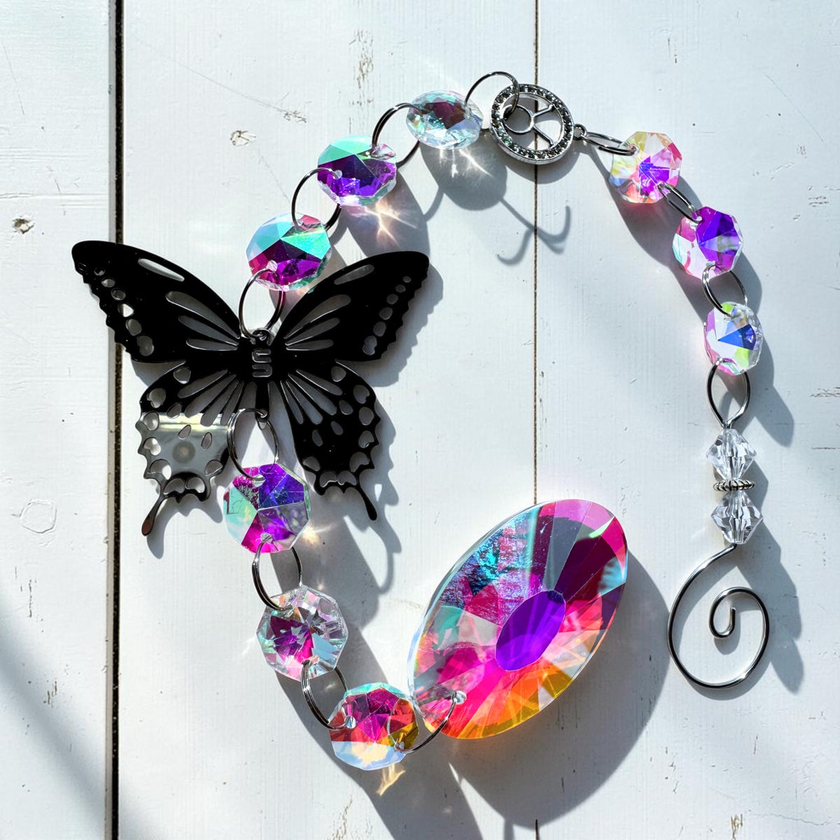 Star sign sun catcher featuring a black butterfly and iridescent glass beads reflecting sunlight.