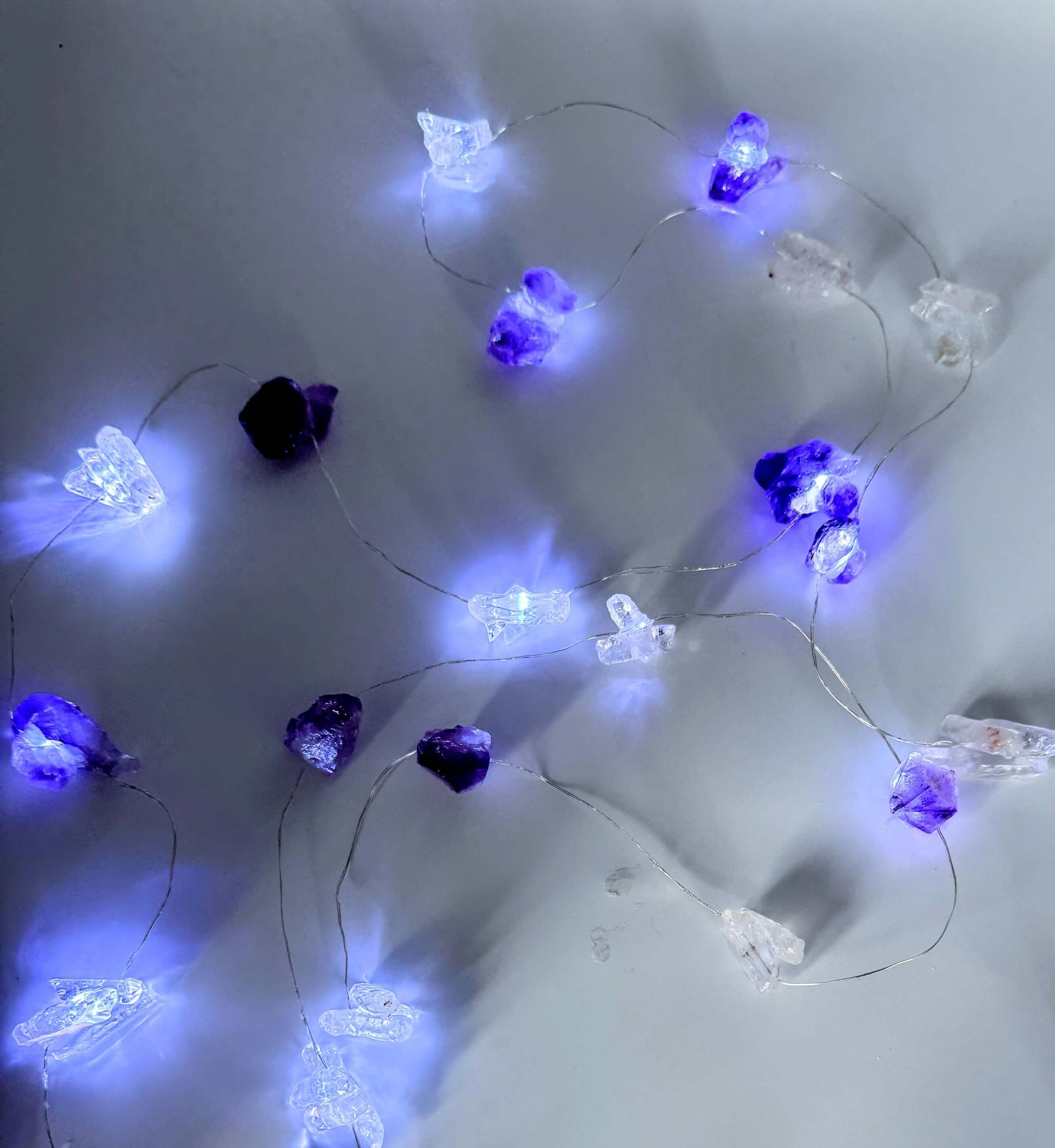 Crystal fairy lights featuring amethyst and clear quartz, glowing with cool white light, 3 meters long with 8 flash settings.