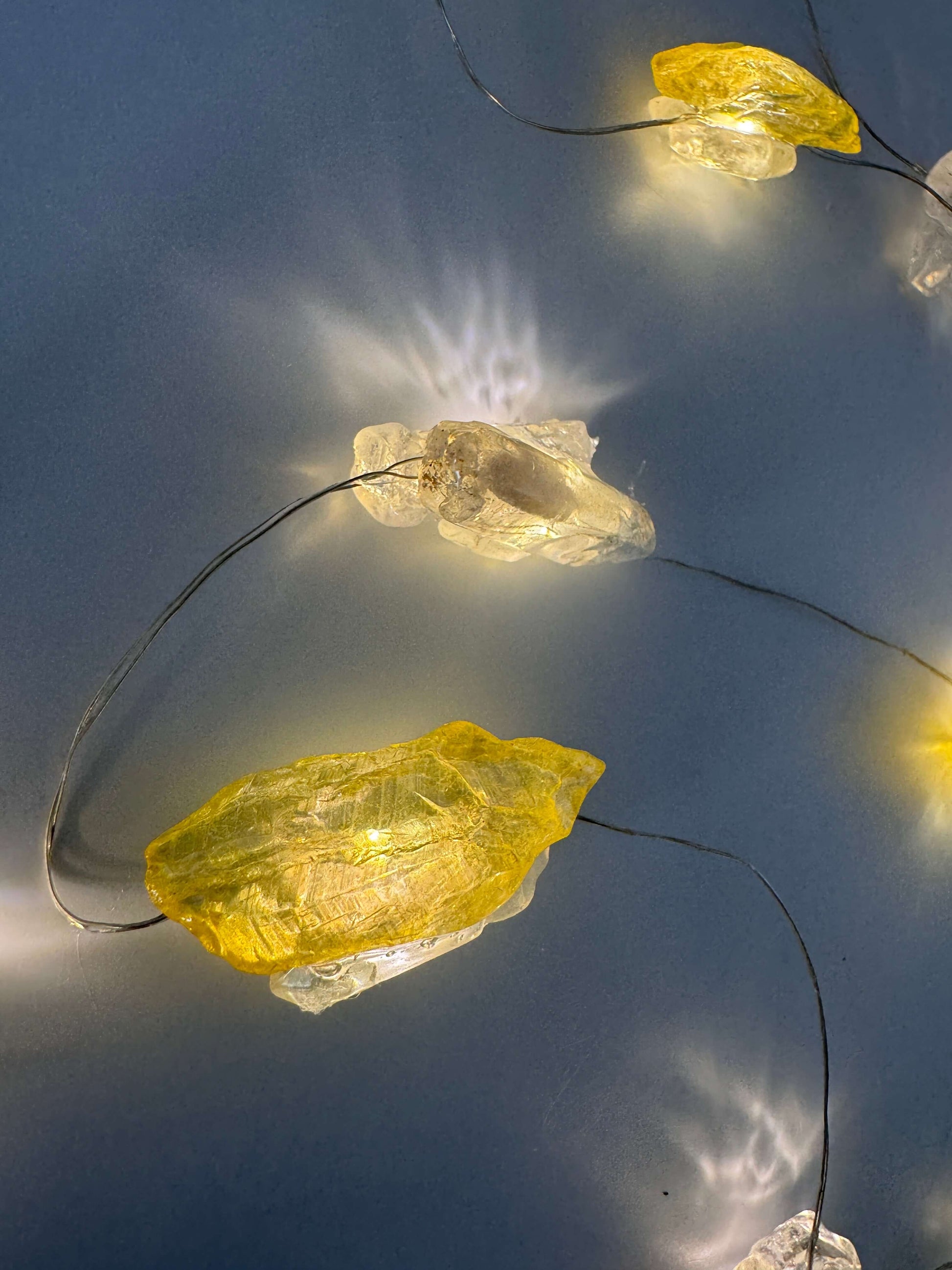 Crystal fairy lights featuring yellow aura quartz and clear quartz, 3 meters long, glowing on dark background.