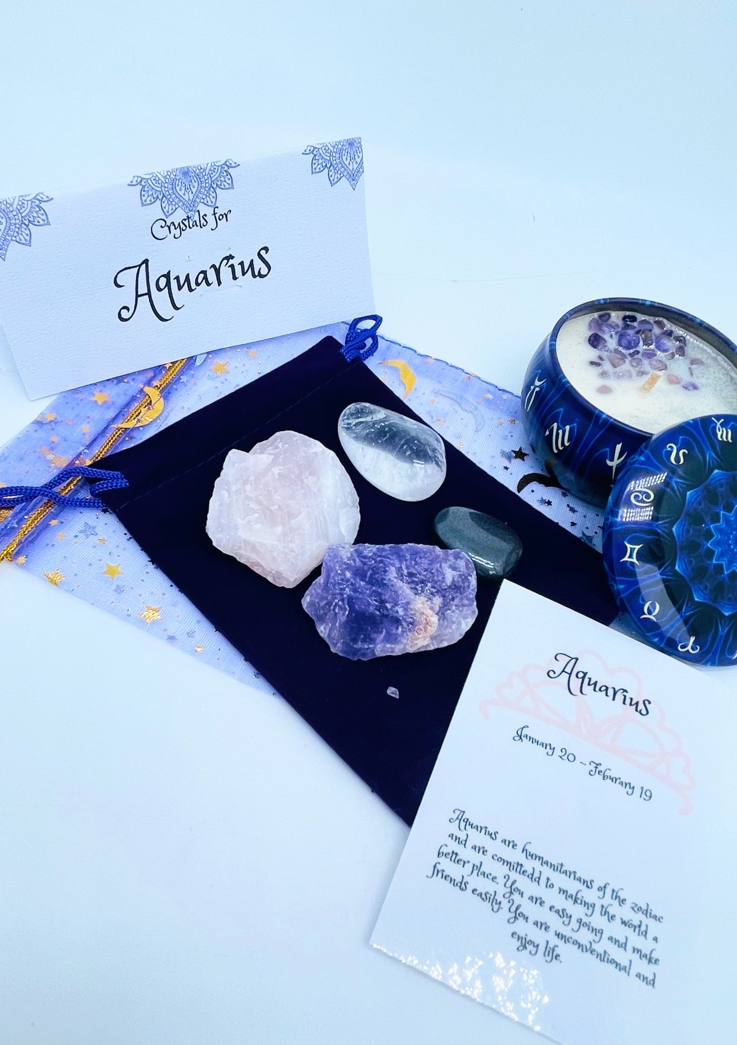 Aquarius zodiac candle gift set with candle and four crystals for this sign sitting on a velvet bag.