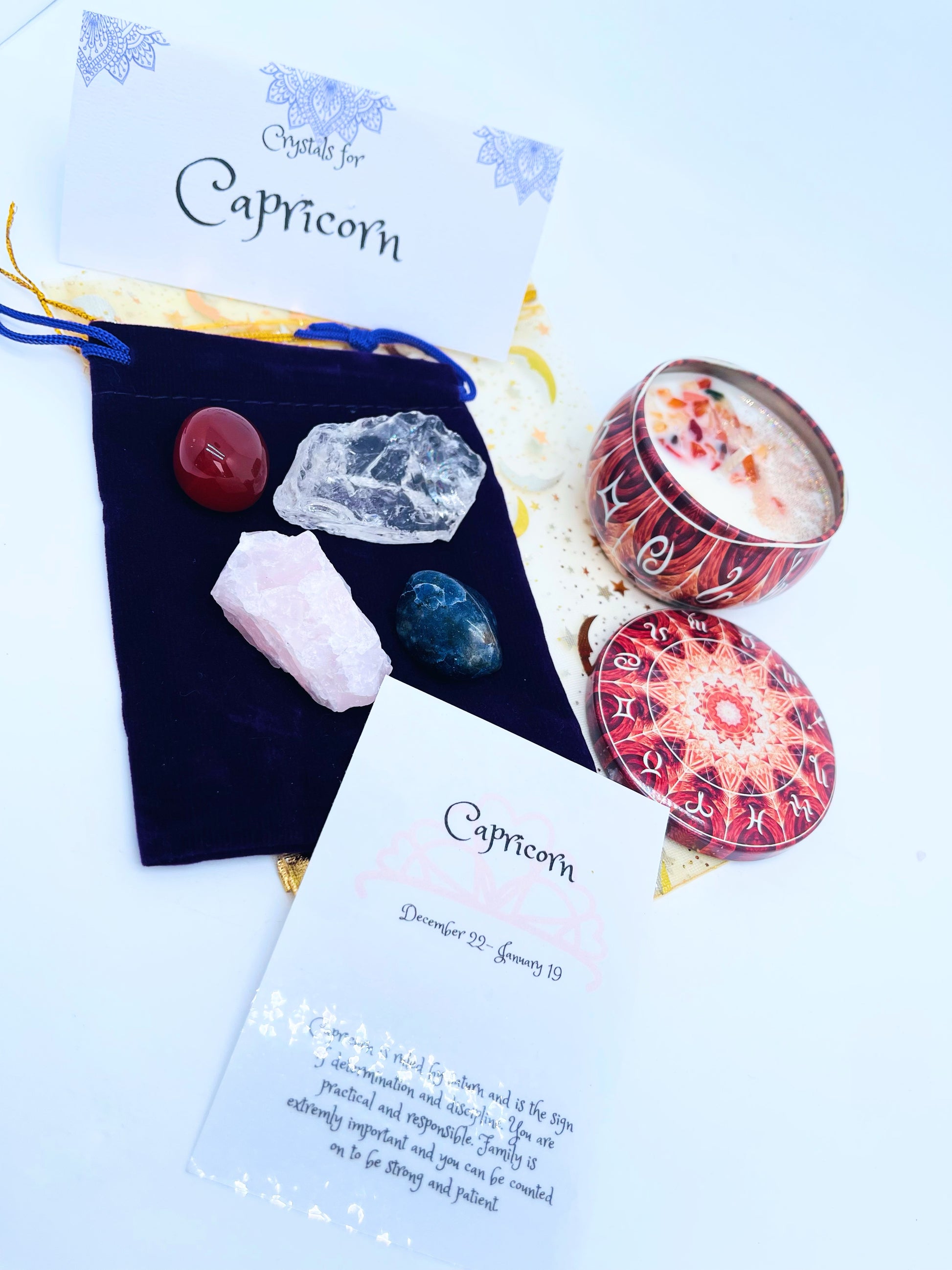 Capricorn zodiac candle gift set with candle and four crystals for this sign sitting on a velvet bag.
