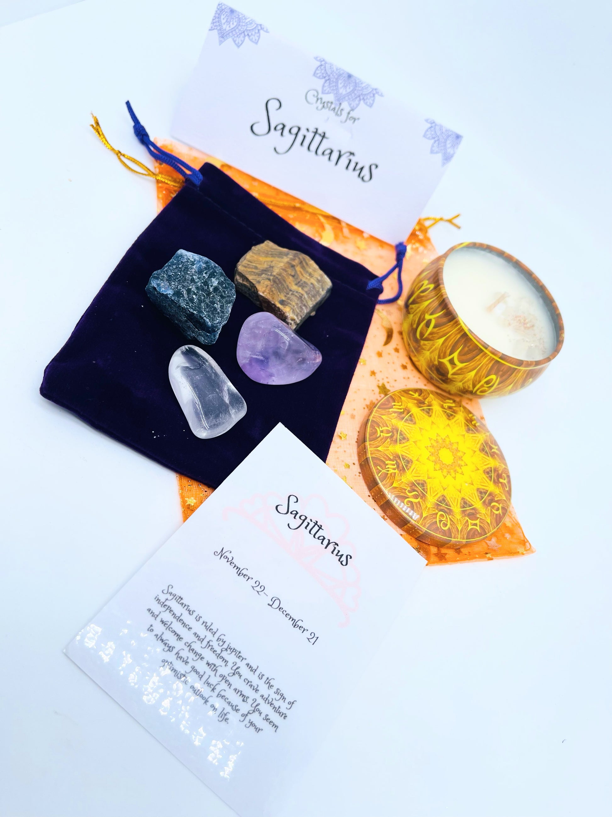 Sagittarius zodiac candle gift set with candle and four crystals for this sign sitting on a velvet bag.