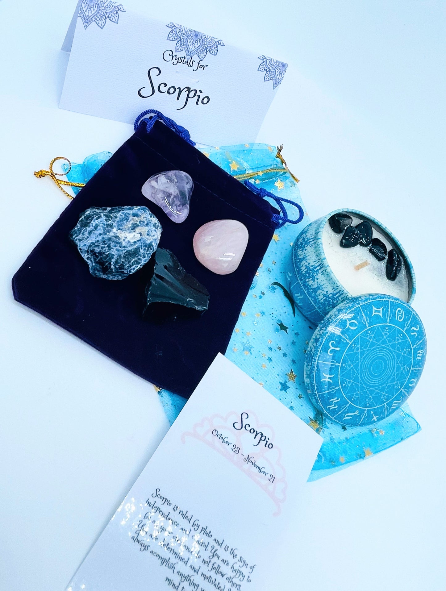 Scorpio zodiac candle gift set with candle and four crystals for this sign sitting on a velvet bag.
