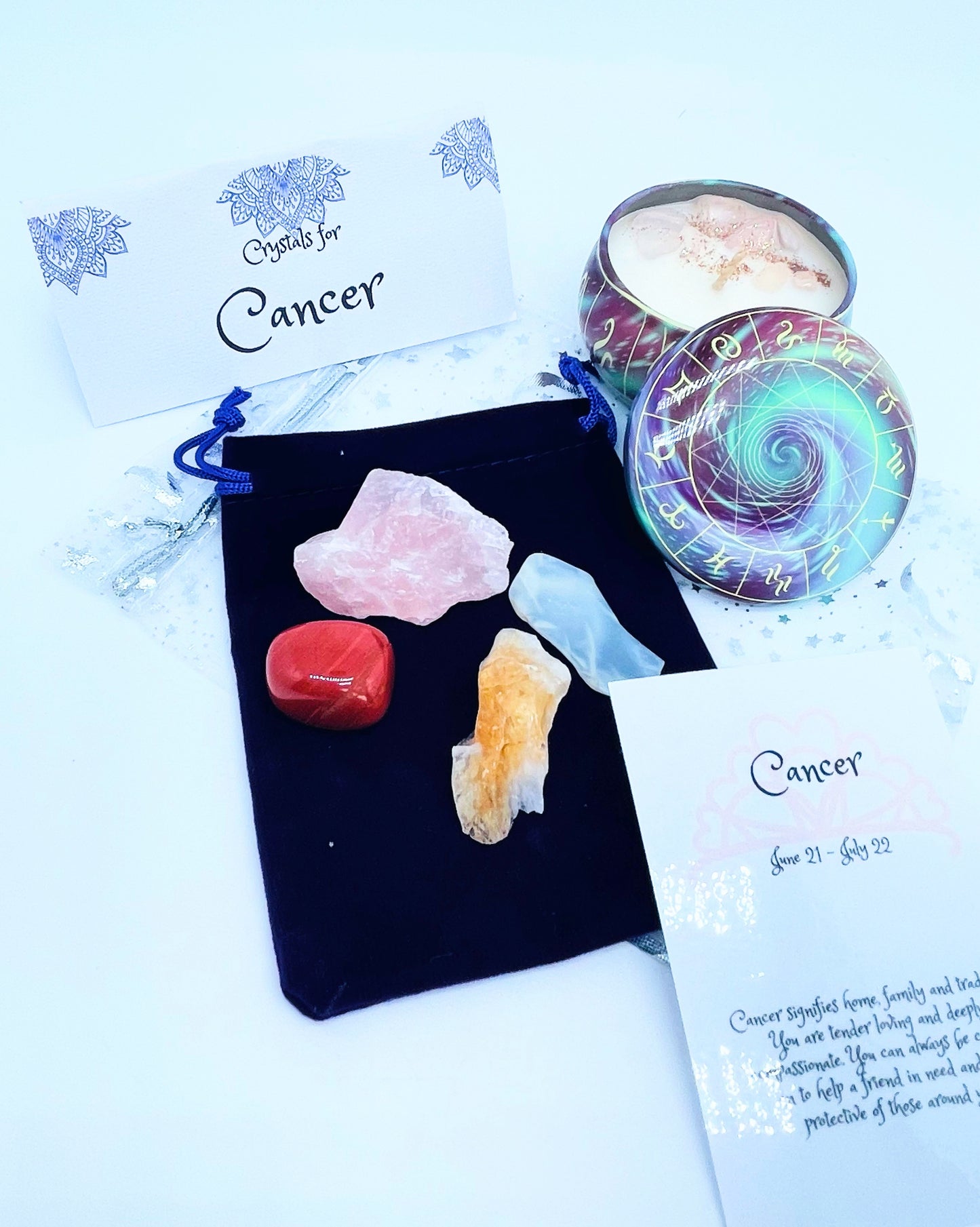 Cancer zodiac candle gift set with candle and four crystals for this sign sitting on a velvet bag.